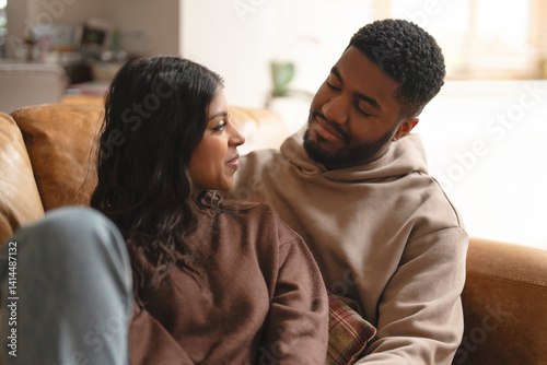 Couple sharing a moment of affection on a cozy couch in a bright living room during a relaxed afternoon in their home