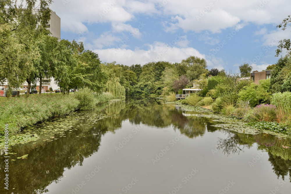 A serene view of a river reflecting lush greenery and buildings, showcasing a harmonious blend of nature and urban life. A serene view of a river reflecting lush greenery and buildings, showcasing a harmonious blend of nature and urban life.