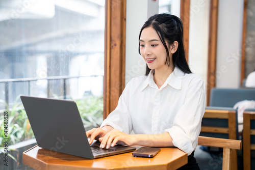 Young woman working on laptop at cafe professional focused and enjoying casual workplace