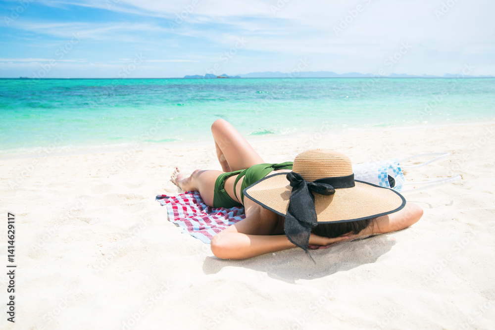 Obraz premium Long shot Women tan skin being sunbathe wearing a green bikini swimsuit straw hat close a face on the beach with seaside. Concept of comfortable holidays vacations and relaxing travel. Copy space.