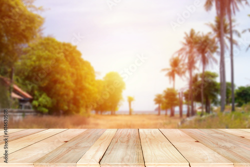 Wooden board empty table on the front with blurred Coconut tree forest on the seaside bokeh background. Empty space for text or product. Product for Health and food. natural concept.