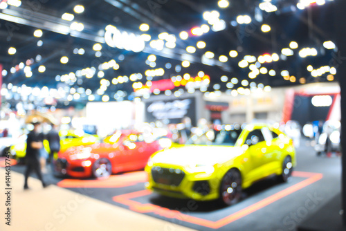 Defocused blurry crowd anonymous people walking at exhibition trade fair at convention event or conference hall. light bokeh background.