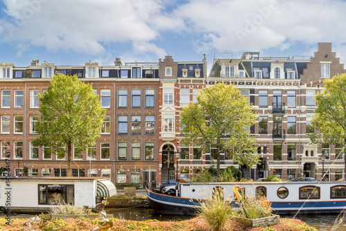 Wallpaper Mural A picturesque view of historic buildings lining a serene canal, framed by lush trees and a peaceful waterway, ideal for tranquil moments and photography. Torontodigital.ca