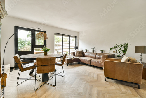 A stylish modern living room featuring a cozy leather sofa  a wooden dining table  and lush indoor plants  combining comfort with contemporary design aesthetics.