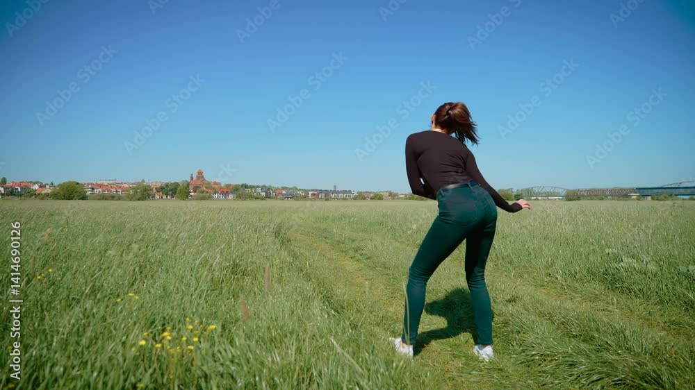 Woman performing energetic dance in grassy field, dynamically rotating hips with enthusiasm. Female showcasing lively and spirited movements, emphasizing rhythm and flow. Lady expressing joy and Woman performing energetic dance in grassy field, dynamically rotating hips with enthusiasm. Female showcasing lively and spirited movements, emphasizing rhythm and flow. Lady expressing joy and