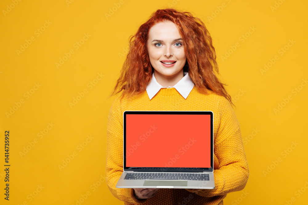Naklejka premium Young redhead IT woman she wear sweater white shirt casual clothes hold use work on laptop pc computer with blank screen workspace area isolated on plain yellow background studio. Lifestyle concept.