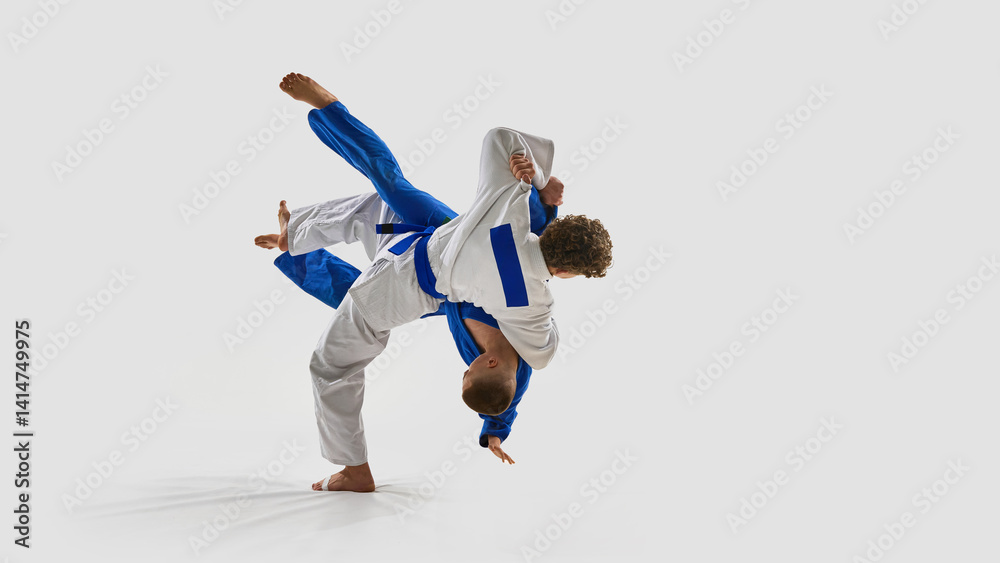 Εκτύπωση καμβά Energetic photo of judoka in white executes full-body rotation throw, opponent elevated off ground, representing precision against white background