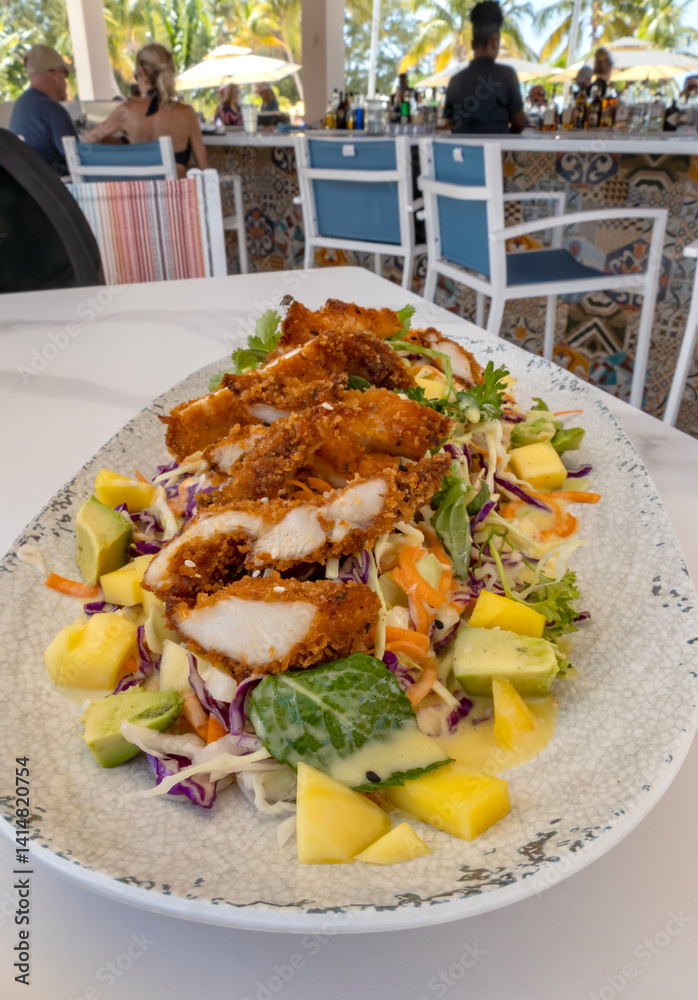 Deep Fried Chicken Breast on Top of a Bed of Fruit and Vegetable Salad Served in a Beach Restaurant