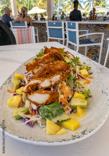 Obraz na płótnie Deep Fried Chicken Breast on Top of a Bed of Fruit and Vegetable Salad Served in a Beach Restaurant w salonie