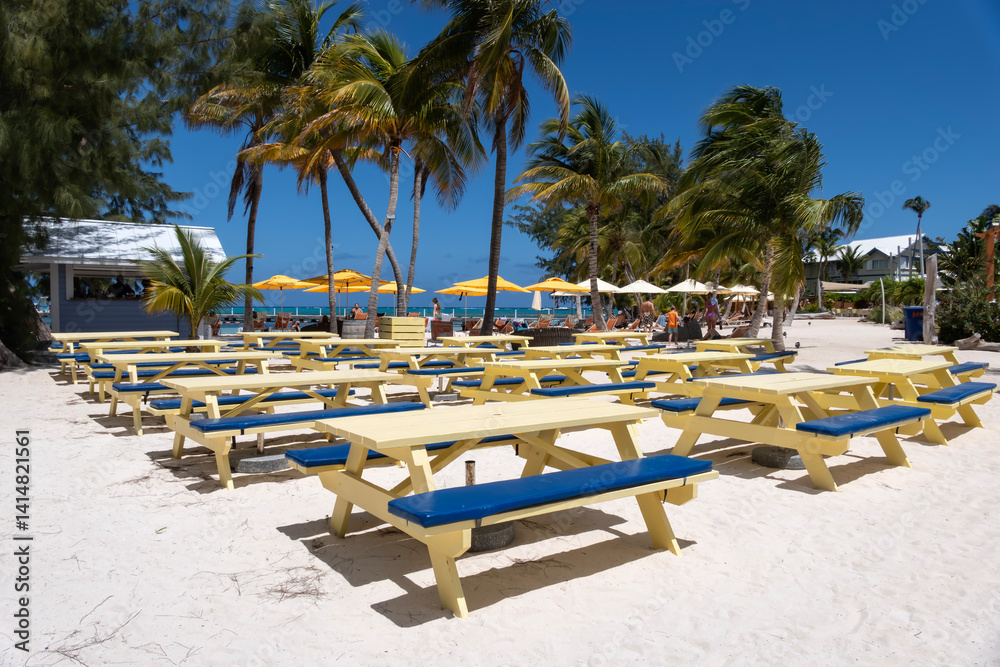 Rows of Colorful Yellow Picnic Tables on White Sandy Beach of Rum Point in Grand Cayman Island