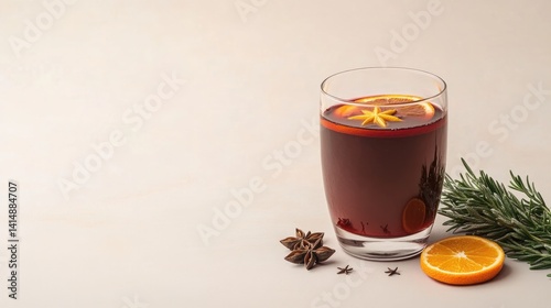 Warm beverage in glass garnished with orange slice and spices ev