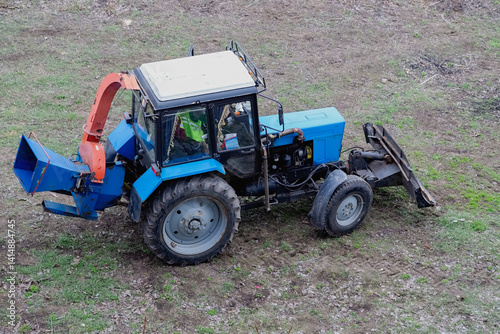 Agricultural special machinery — a tractor with a wood chipper is situated in an open area. Eco-friendly disposal of branches using specialized machines helps maintain cleanliness photo