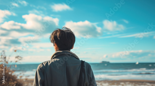 A person stands on the beach gazing at the shore on the morning