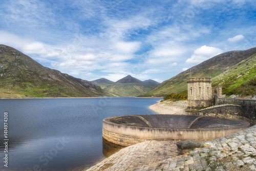 This breathtaking landscape showcases stunning, serene Silent Valley Reservoir, beautifully nestled between lush green mountains that rise majestically under vibrant blue sky, Newry, Northern Ireland