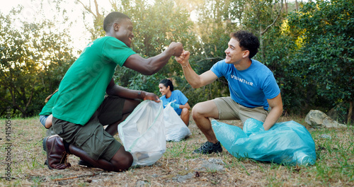 People, fist bump and volunteer community in nature for eco friendly environment, success or mission outdoors. Group, friends and celebration in team building, unity or charity collaboration in park