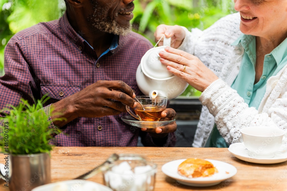 A couple enjoying tea outdoors. A man and woman share a moment over tea. Smiling and relaxed, they pour tea and chat. Tea time brings joy and connection. Diverse couple drinking tea.
