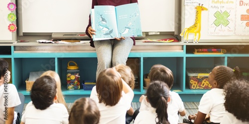 Fotografie Teacher reading to diverse children in a classroom