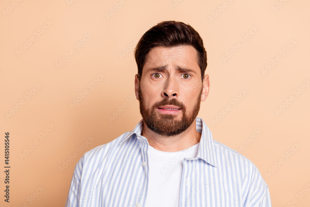Obraz premium Portrait of a Young Man With Beard and Casual Outfit Expressing a Surprised Facial Gesture in Front of a Neutral Beige Background