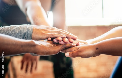 Diverse group of people, putting hands together in a team huddle. Diverse group, teamwork, and unity in fitness. Diverse group bonding. Exercise for better health. Team stacking hands in huddle.
