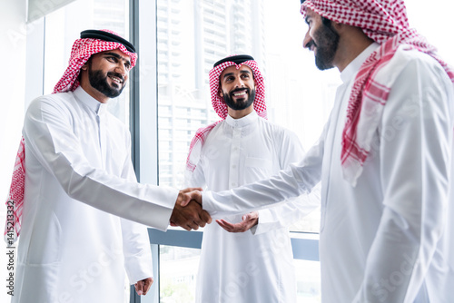 Arab businessmen wearing saudi kandura meeting in office for business deal - Corporate business group of middle-eastern people working in an international company in middle east