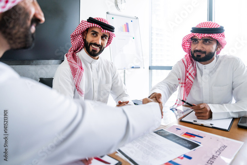 Arab businessmen wearing saudi kandura meeting in office for business deal - Corporate business group of middle-eastern people working in an international company in middle east photo