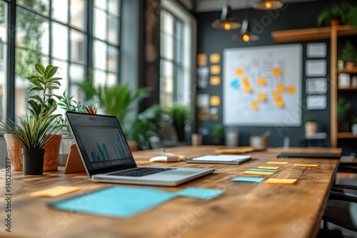 Laptop on wooden table with sticky notes and plants in a modern meeting room