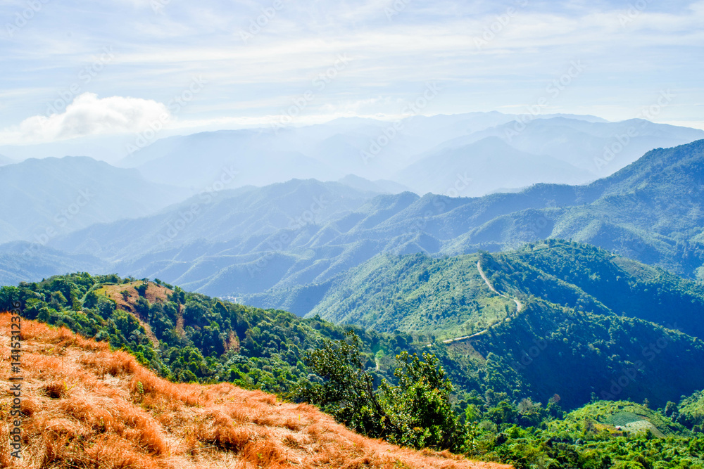 Obraz premium Scenic Mountain Landscape with Blue Sky and Layers of Misty Hills