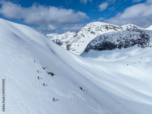 Alpine skiers on their way up to the top, and some skiers on their way down. Norwegian winter mountain landscape.