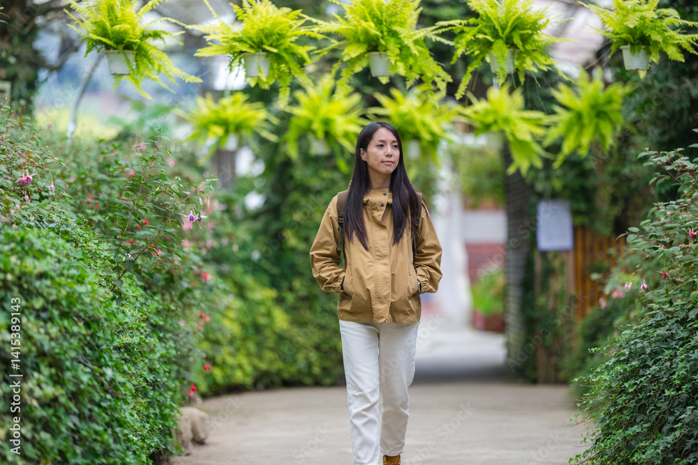 Woman walking through green garden pathway