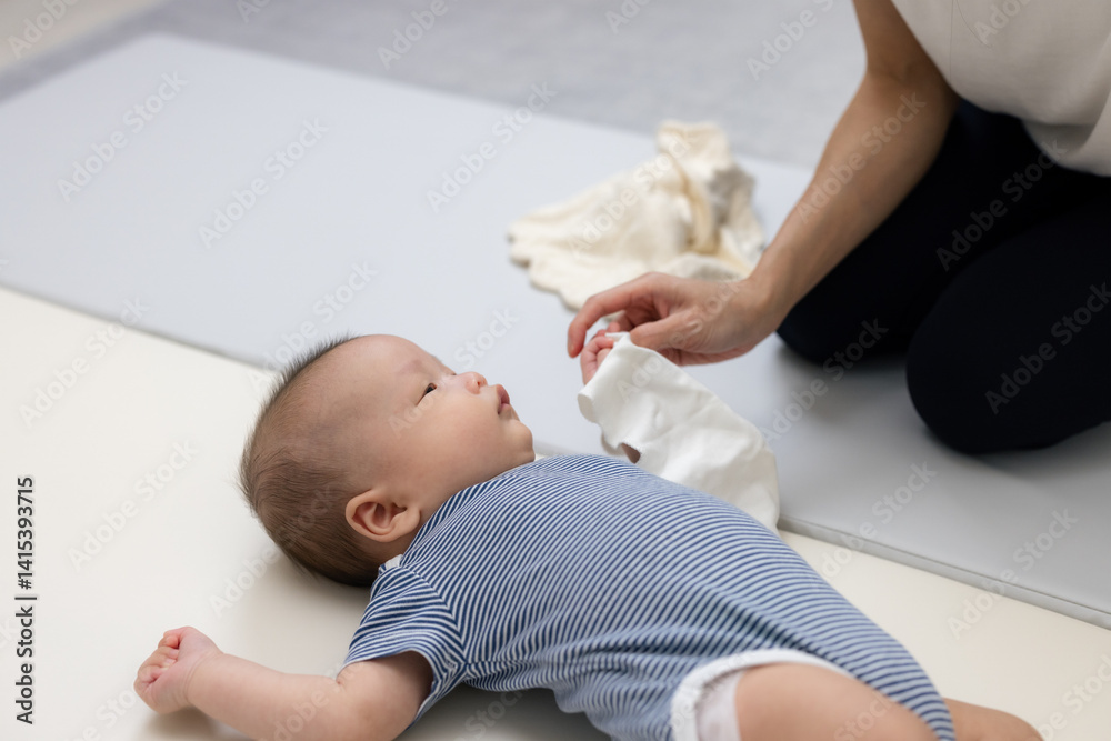 Mum wiping baby with towel in nursery room