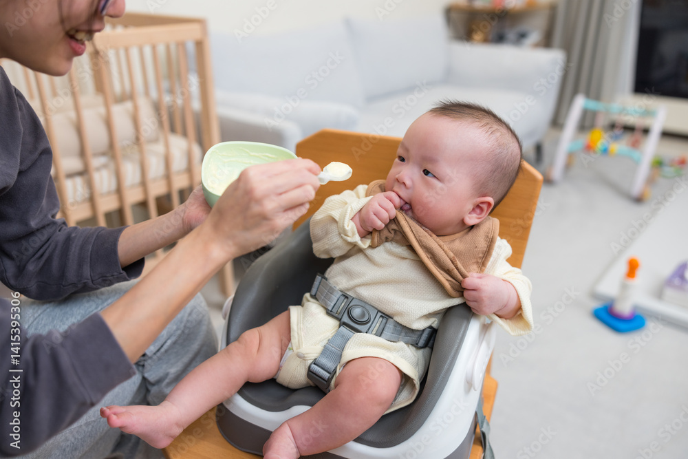 Parent feeding baby sitting on high chair