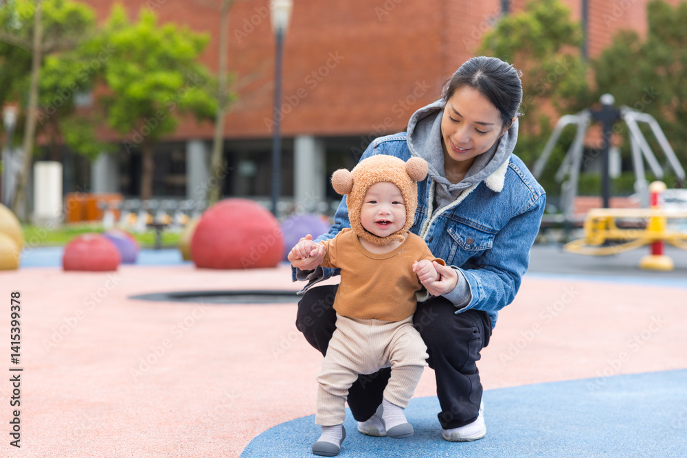 Mother helping baby walk at playground outdoors