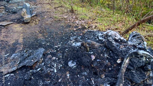 A completely burned car after an accident. Destroyed vehicle with melted body parts and an exploded engine. Charred remains of an automobile showing severe fire damage and destruction.