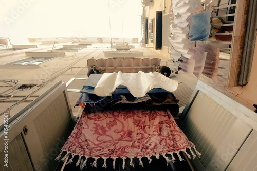 Freshly washed red linens hang from clotheslines stretched between weathered buildings in Naples' Spanish Quarter. Viewed from below. Authentic Italian urban living and neighborhood charm.
