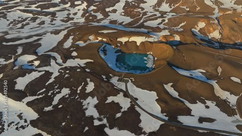 Aerial view of Viti crater in the Krafla volcanic area, Iceland. The turquoise lake contrasts with surrounding snow and brown volcanic terrain.