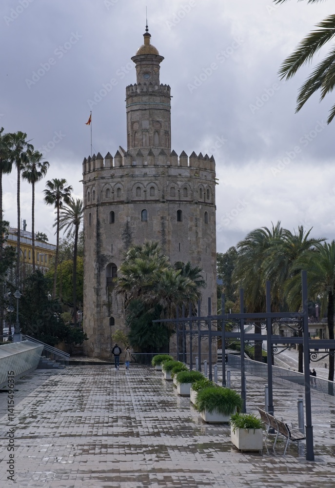 Fototapeta premium Seville, Spain - Mar 23, 2025: Walking in Seville. Torre del Oro (Gold Tower). Streets, buildings. Lifestyle in the urban area. Cloudy spring day. Selective focus