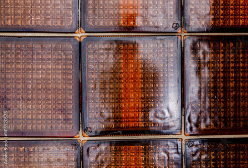 Obraz na płótnie Exploring intricate textures of warm-toned glass tiles with deep shadows and reflections under soft light w salonie