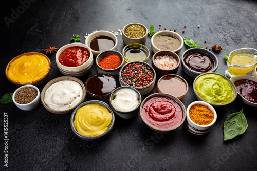 Obraz na płótnie Set of different bowls of various dip sauces, on dark background, top view w salonie