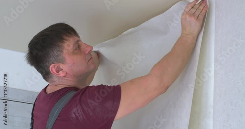 A person who covers the walls with new wallpaper, smoothing them on the wall with a special spatula.