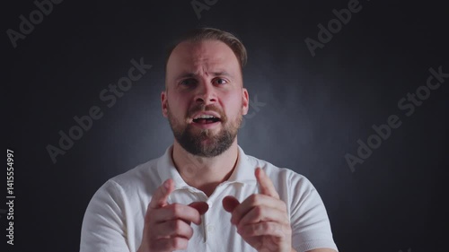 A man with a beard and a white shirt gazes pensively into the distance, his expression reflecting contemplation and introspection.