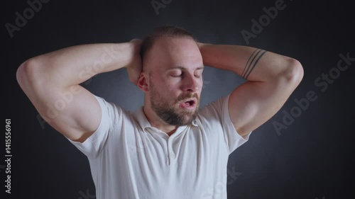 A man in a white shirt holds his head, revealing a look of stress and frustration. The close-up shot intensifies his emotional state.