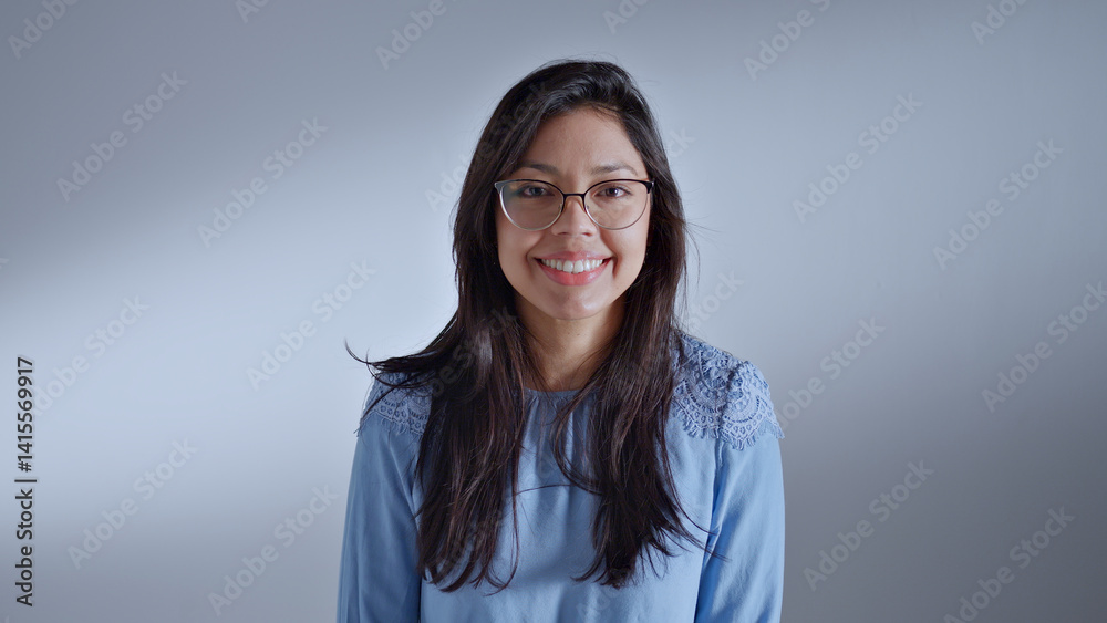 Woman in glasses and blue shirt poses confidently, exuding warmth and approachability. Woman in glasses and blue shirt poses confidently, exuding warmth and approachability.