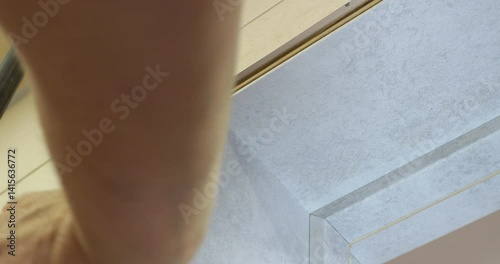 Professional carpenter installing white decorative architrave around door frame, demonstrating woodworking precision through careful measuring, cutting, and securing process
