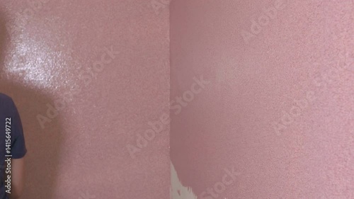 Professional construction worker smoothing pink plaster across white wall surface, demonstrating skilled craftsmanship and precise renovation techniques using specialized spatula