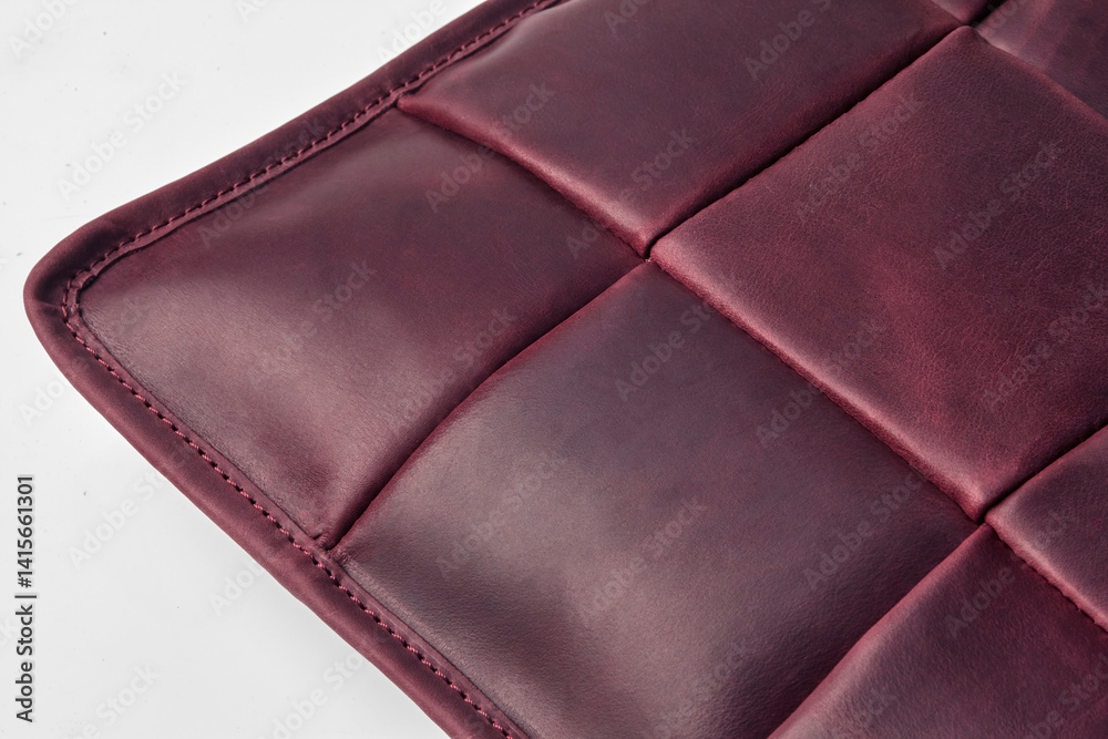 Burgundy leather surface showing stitching and square pattern