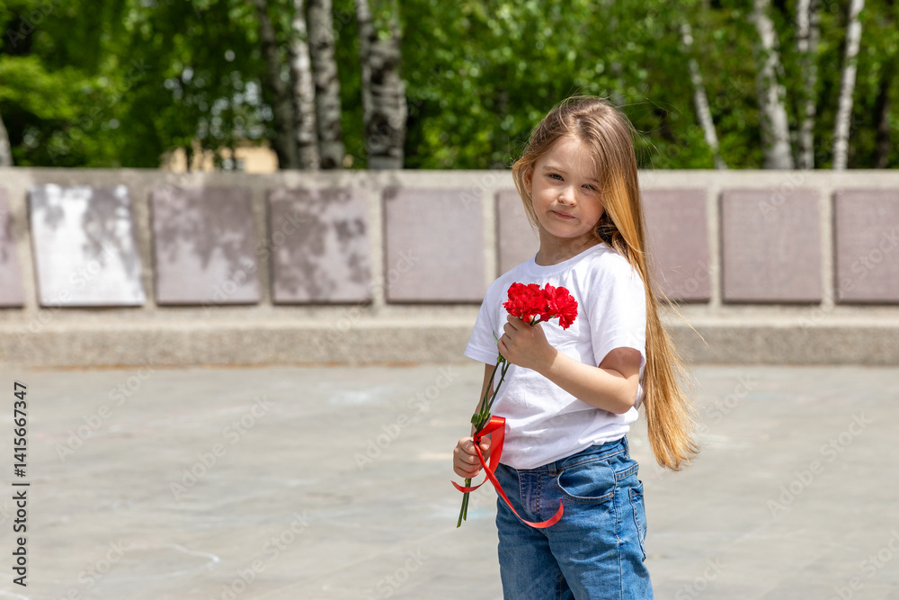 Victory Day. Little Girl with red carnations at the Eternal flame near the monument of Unknown soldiers tomb. Patriotic education at school.