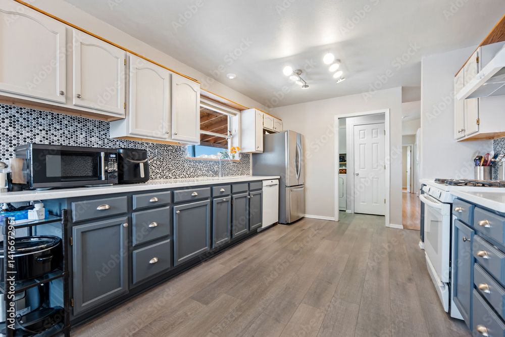 A kitchen with gray cabinets, white countertops, and appliances A kitchen with gray cabinets, white countertops, and appliances