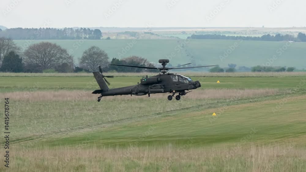 British army AH-64E Boeing Apache Attack helicopter gunship (ZM735 ArmyAirCorp) performing low level hover close to a grass runway British army AH-64E Boeing Apache Attack helicopter gunship (ZM735 ArmyAirCorp) performing low level hover close to a grass runway