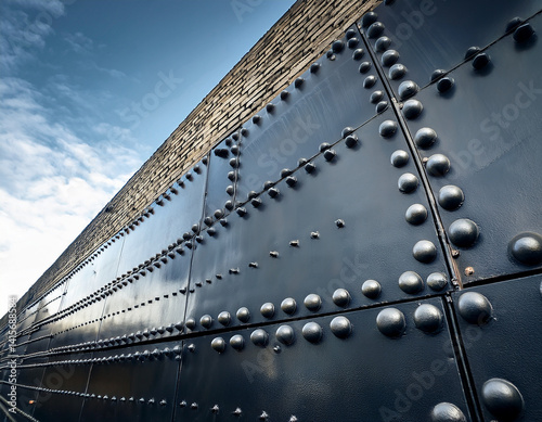 A reinforced metal wall with rivets and bolts, symbolizing authoritarian barriers and rigid political structures.