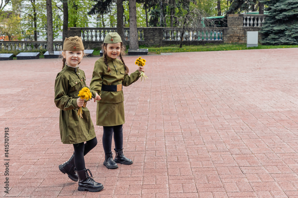 Patriotic education of youth. Little girls in an old Soviet military uniform laying flowers at the eternal flame near the monument to fallen soldiers in world War II. Victory Day on May 9. Copy space